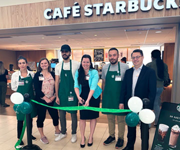 Plan large d'un groupe d'employés qui coupe le ruban menant au Starbuck